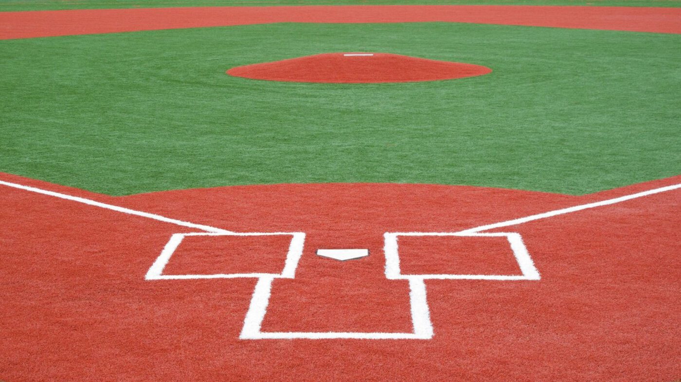 A view of a baseball field showing the pitcher's mound, home plate, and batter's boxes, all outlined in white on vibrant artificial turf by a Top-Rated Artificial Grass Installer Phoenix.