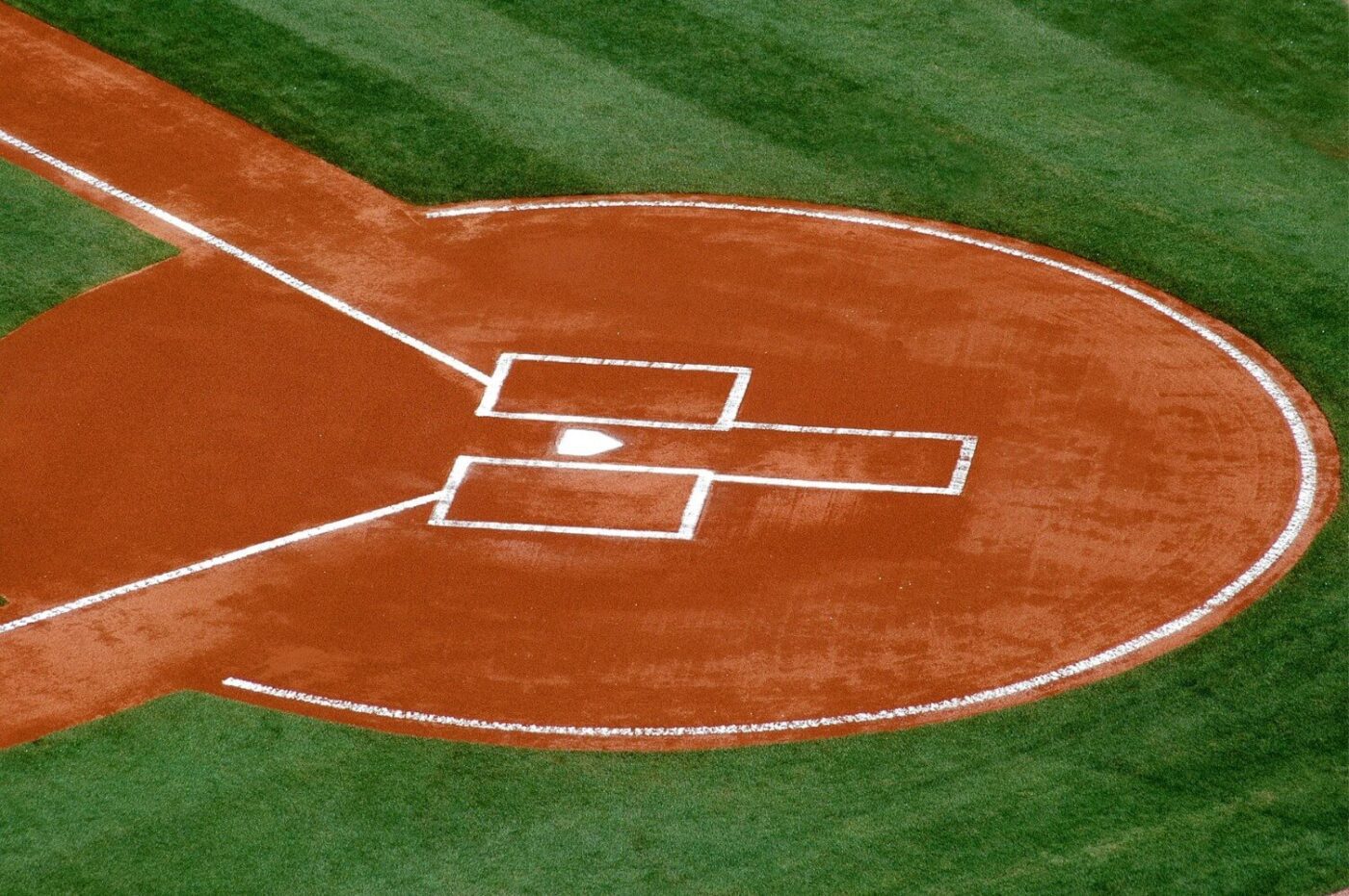 Aerial view of a baseball field’s home plate area, featuring the dirt diamond, white chalk baselines, batter’s boxes, and lush green turf installed by a Top-Rated Artificial Grass Installer Phoenix.